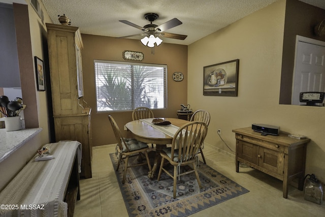 tiled dining space featuring a textured ceiling and ceiling fan