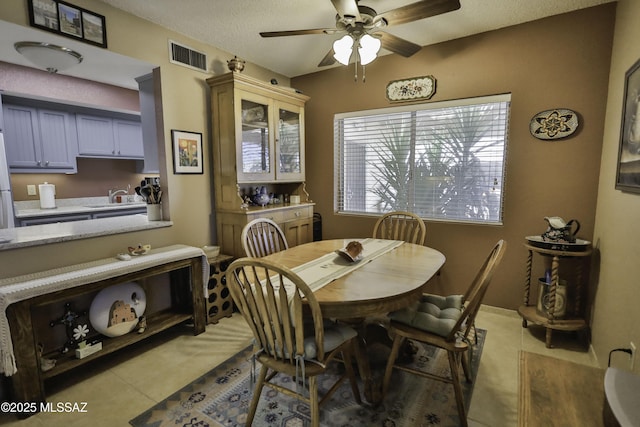 tiled dining room featuring ceiling fan, sink, and a textured ceiling