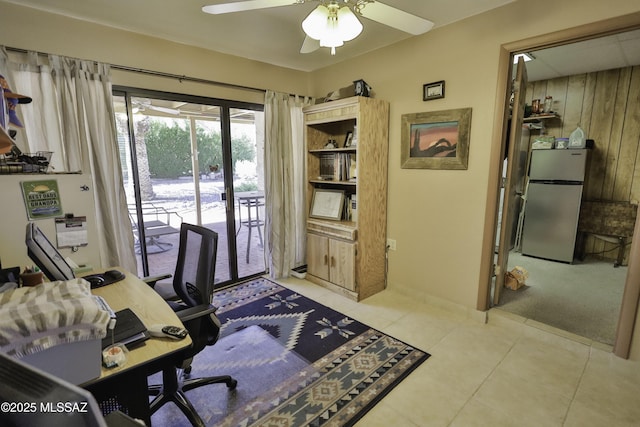 tiled office space featuring ceiling fan and wooden walls