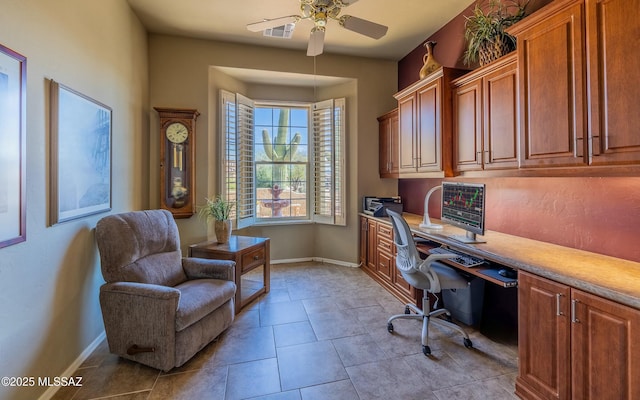 tiled office space with built in desk, a ceiling fan, and baseboards