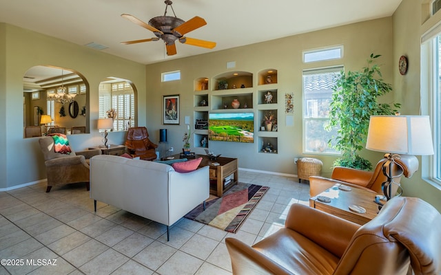 living room featuring light tile patterned floors, visible vents, built in features, arched walkways, and baseboards