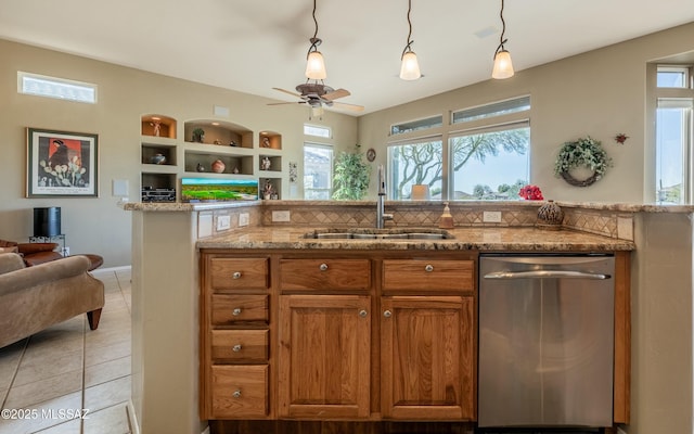 kitchen featuring a sink, open floor plan, stainless steel dishwasher, light stone countertops, and brown cabinetry