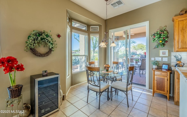 dining room with light tile patterned floors, wine cooler, plenty of natural light, and visible vents