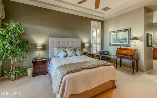 carpeted bedroom featuring a ceiling fan, baseboards, visible vents, and a tray ceiling