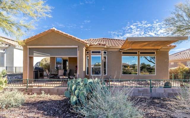 back of property with a tile roof, fence, a patio, and stucco siding