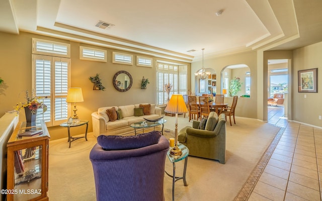 living area with light tile patterned floors, a raised ceiling, visible vents, and a healthy amount of sunlight