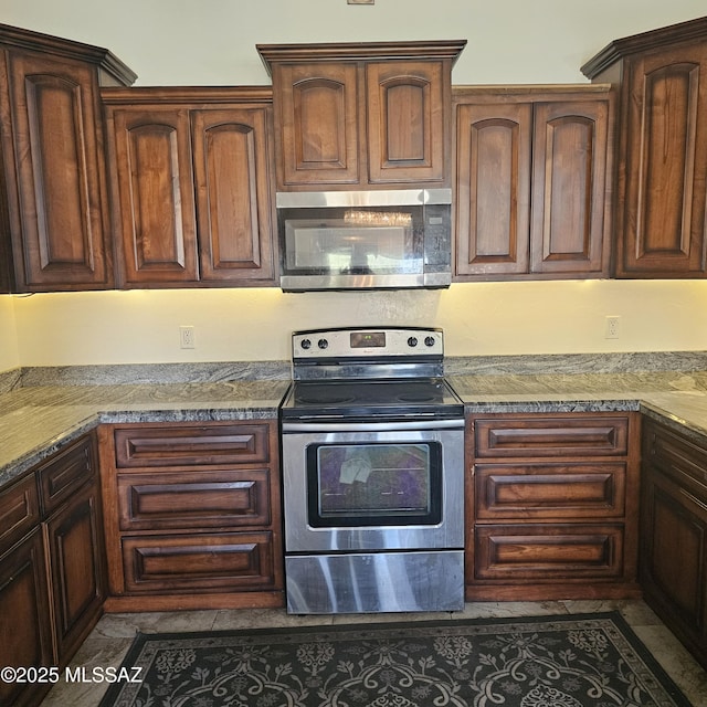 kitchen with light stone countertops, dark tile patterned floors, and stainless steel appliances