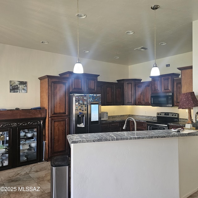 kitchen featuring dark stone counters, appliances with stainless steel finishes, dark brown cabinets, and pendant lighting