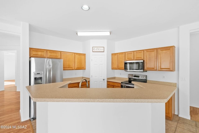 kitchen featuring appliances with stainless steel finishes, light tile patterned floors, a kitchen island, and sink