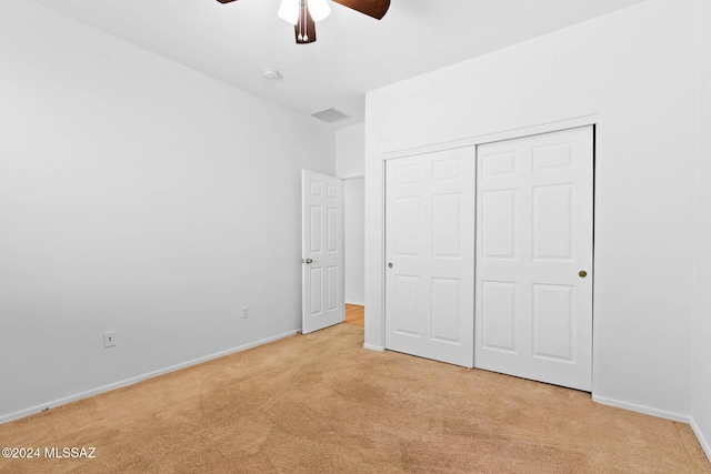 unfurnished bedroom with ceiling fan, light colored carpet, and a closet