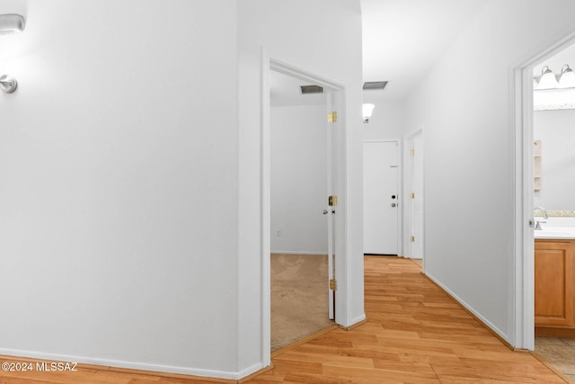 hallway featuring sink and light colored carpet