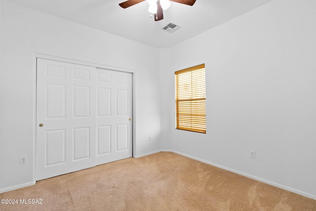 unfurnished bedroom with light carpet, a closet, and ceiling fan