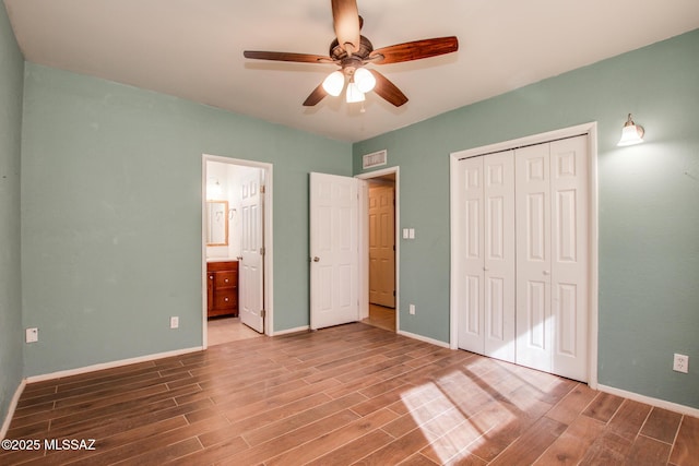 unfurnished bedroom with hardwood / wood-style flooring, ceiling fan, ensuite bathroom, and a closet