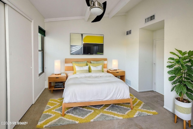 carpeted bedroom featuring beamed ceiling, a closet, and ceiling fan