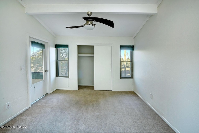 unfurnished bedroom with multiple windows, vaulted ceiling with beams, light carpet, and ceiling fan