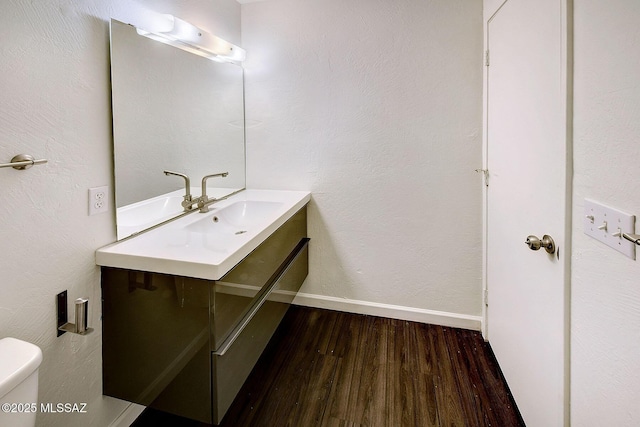 bathroom with vanity, toilet, and hardwood / wood-style floors