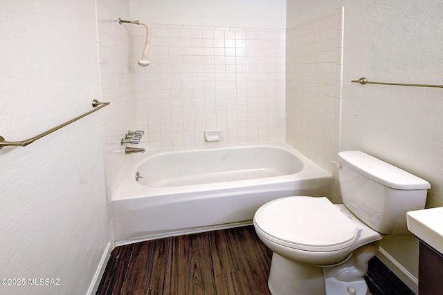 full bathroom featuring vanity, hardwood / wood-style floors, tiled shower / bath, and toilet