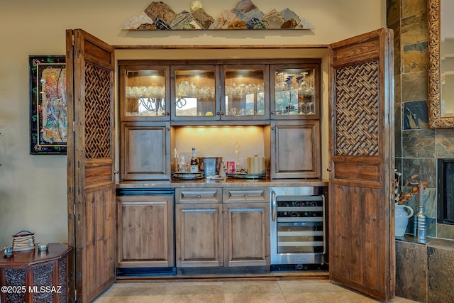 bar with wine cooler and dark brown cabinetry