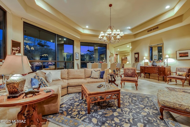 living room with light tile patterned flooring, a chandelier, a towering ceiling, and a tray ceiling