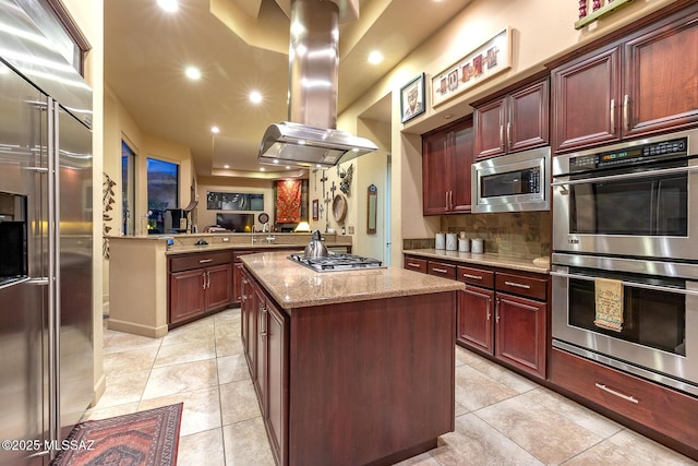 kitchen with a kitchen island, kitchen peninsula, light tile patterned flooring, island exhaust hood, and built in appliances