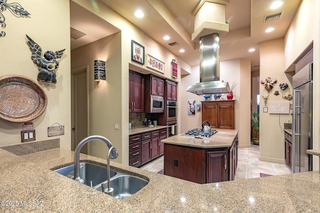 kitchen featuring appliances with stainless steel finishes, backsplash, a center island, light stone countertops, and sink