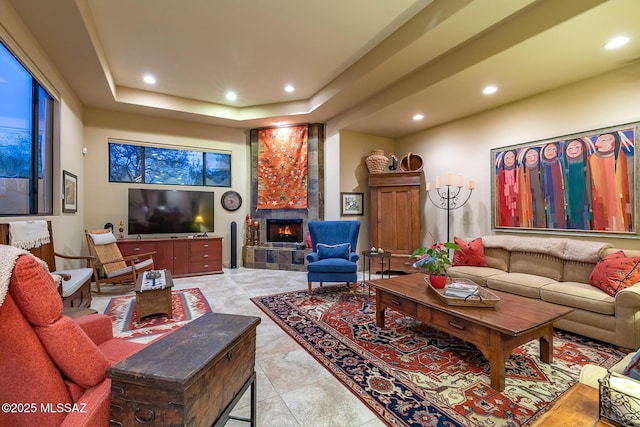 living room with a raised ceiling and a tiled fireplace