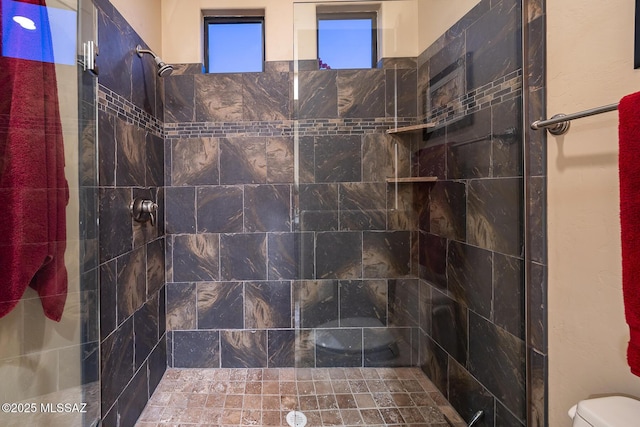 bathroom featuring toilet and tiled shower