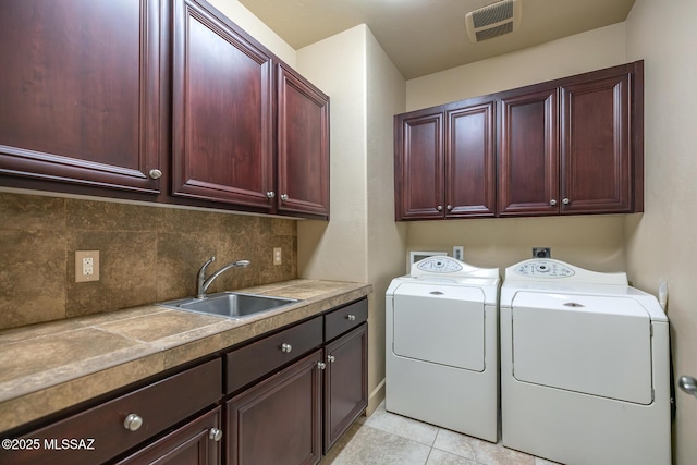 clothes washing area featuring light tile patterned floors, sink, separate washer and dryer, and cabinets