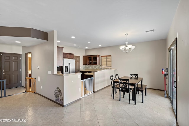 7585 E Majestic Palm Ln, Tucson, AZ 85756 - kitchen featuring stainless steel refrigerator with ice dispenser, a chandelier, light countertops, backsplash, and glass insert cabinets