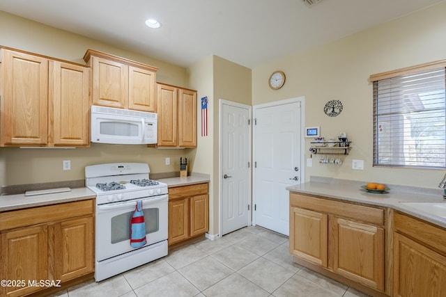 kitchen featuring light brown cabinetry, sink, light tile patterned floors, and white appliances