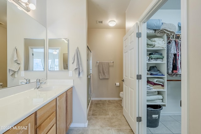 bathroom with tile patterned flooring, vanity, toilet, and walk in shower