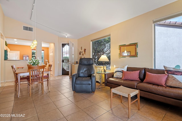 living room featuring lofted ceiling, rail lighting, and light tile patterned flooring