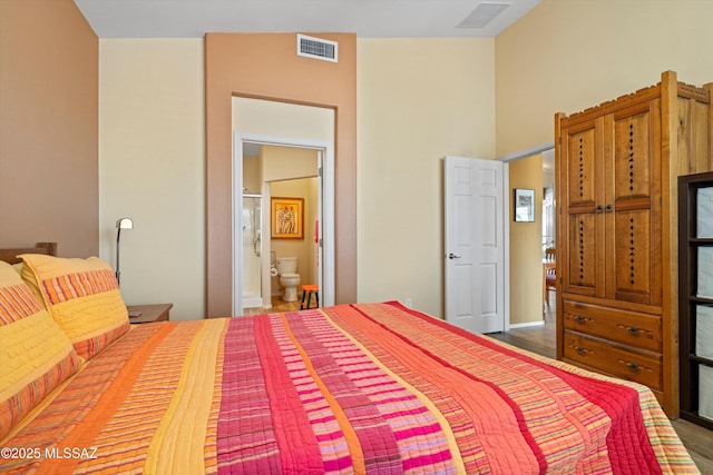 bedroom with connected bathroom and dark hardwood / wood-style floors