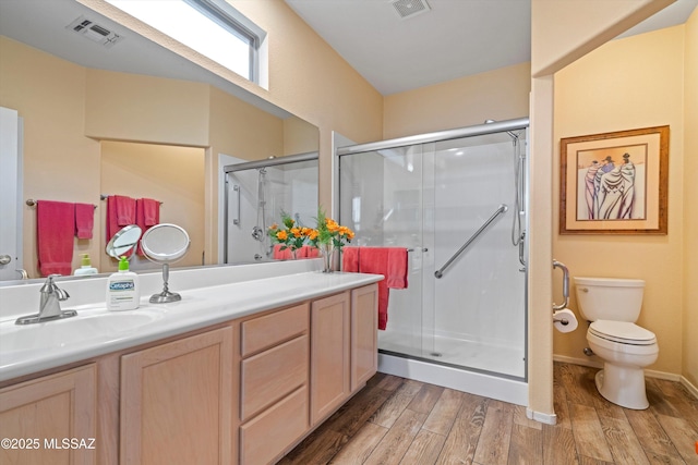 bathroom featuring a shower with door, wood-type flooring, vanity, and toilet