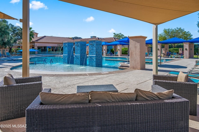 view of swimming pool with pool water feature, outdoor lounge area, and a patio area