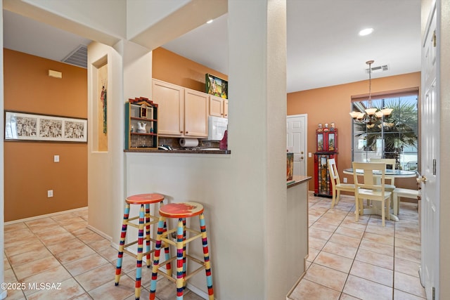 kitchen with an inviting chandelier, decorative light fixtures, light brown cabinetry, and light tile patterned floors