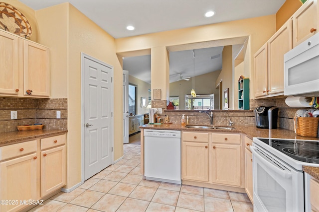 kitchen featuring sink, dark stone counters, light tile patterned floors, kitchen peninsula, and white appliances