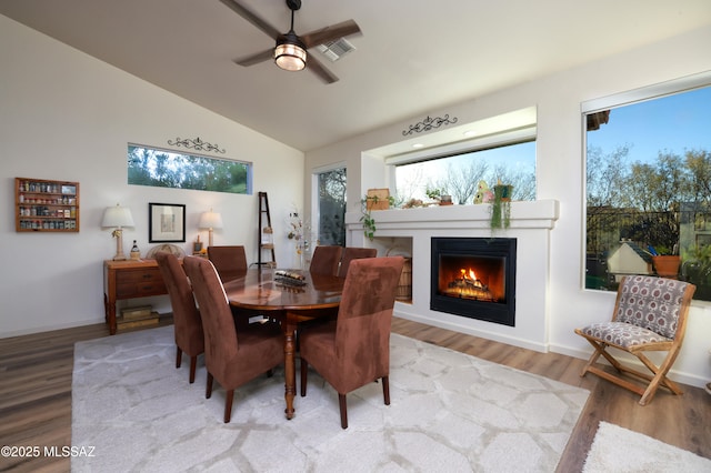 dining space with vaulted ceiling, ceiling fan, a wealth of natural light, and hardwood / wood-style floors