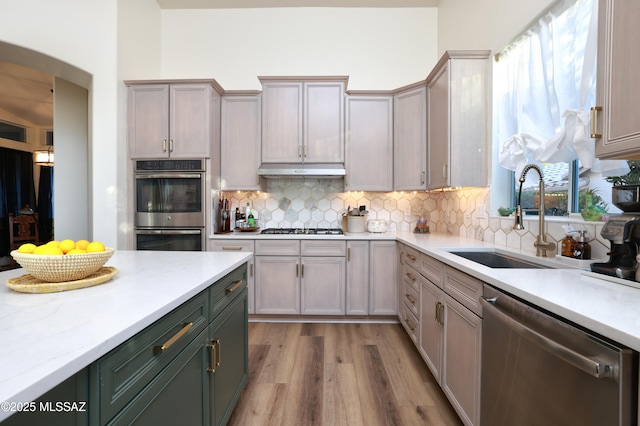 kitchen featuring stainless steel appliances, light hardwood / wood-style floors, sink, backsplash, and gray cabinetry