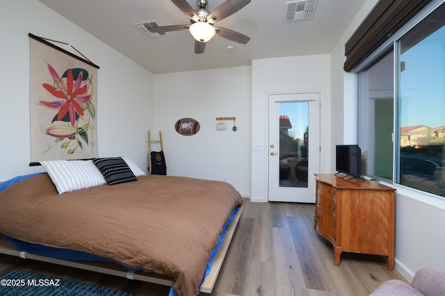 bedroom featuring ceiling fan, light hardwood / wood-style floors, and multiple windows