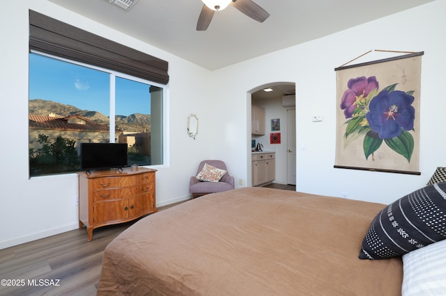 bedroom with ceiling fan, dark wood-type flooring, and ensuite bath