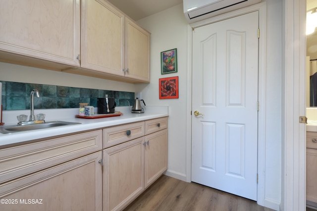 kitchen featuring light brown cabinets, sink, backsplash, a wall unit AC, and light hardwood / wood-style flooring