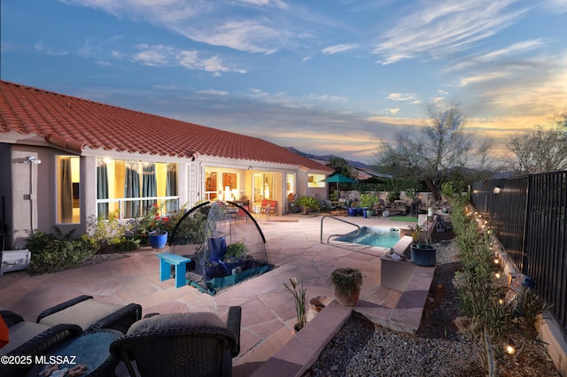 pool at dusk with a patio area