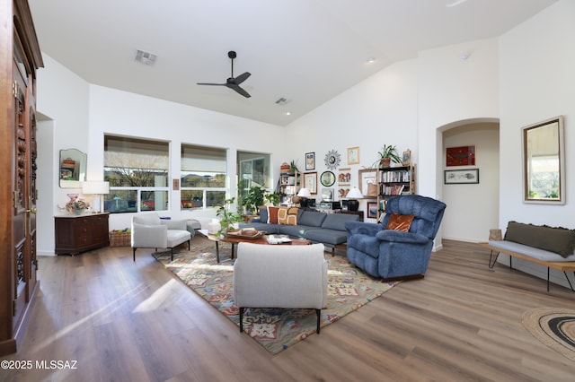 living room with a high ceiling, ceiling fan, and wood-type flooring