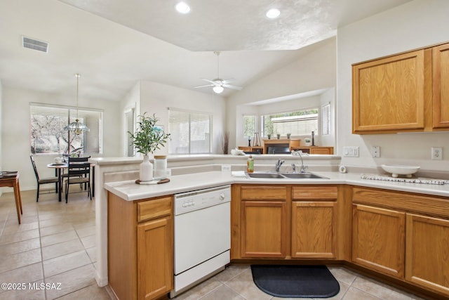 kitchen featuring vaulted ceiling, dishwasher, sink, light tile patterned floors, and kitchen peninsula