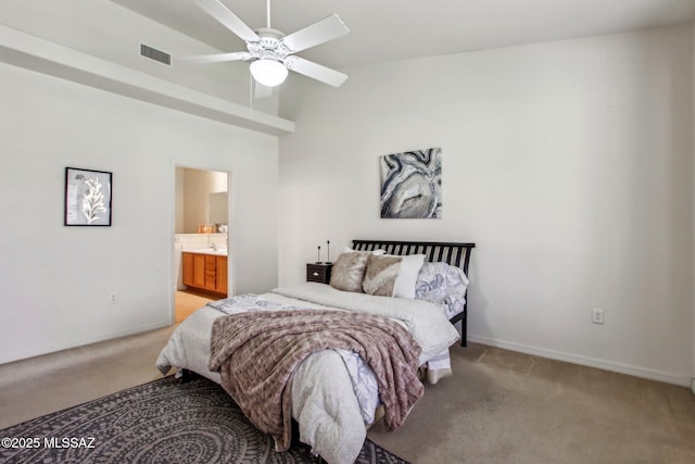 bedroom featuring a high ceiling, ceiling fan, light carpet, and ensuite bath