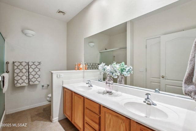 bathroom with tile patterned flooring, vanity, a shower with shower door, and toilet