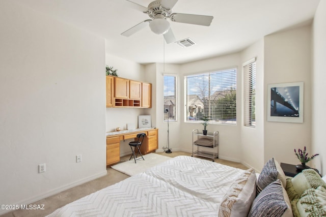 carpeted bedroom with built in desk and ceiling fan