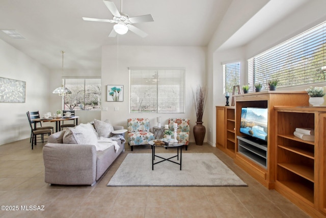 living room with light tile patterned flooring, lofted ceiling, and ceiling fan with notable chandelier