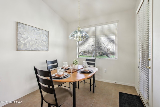 dining room featuring light tile patterned flooring, vaulted ceiling, and an inviting chandelier